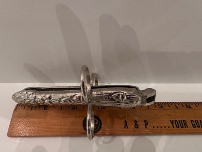 Silver plate asparagus utensil beside a ruler spanning roughly five inches