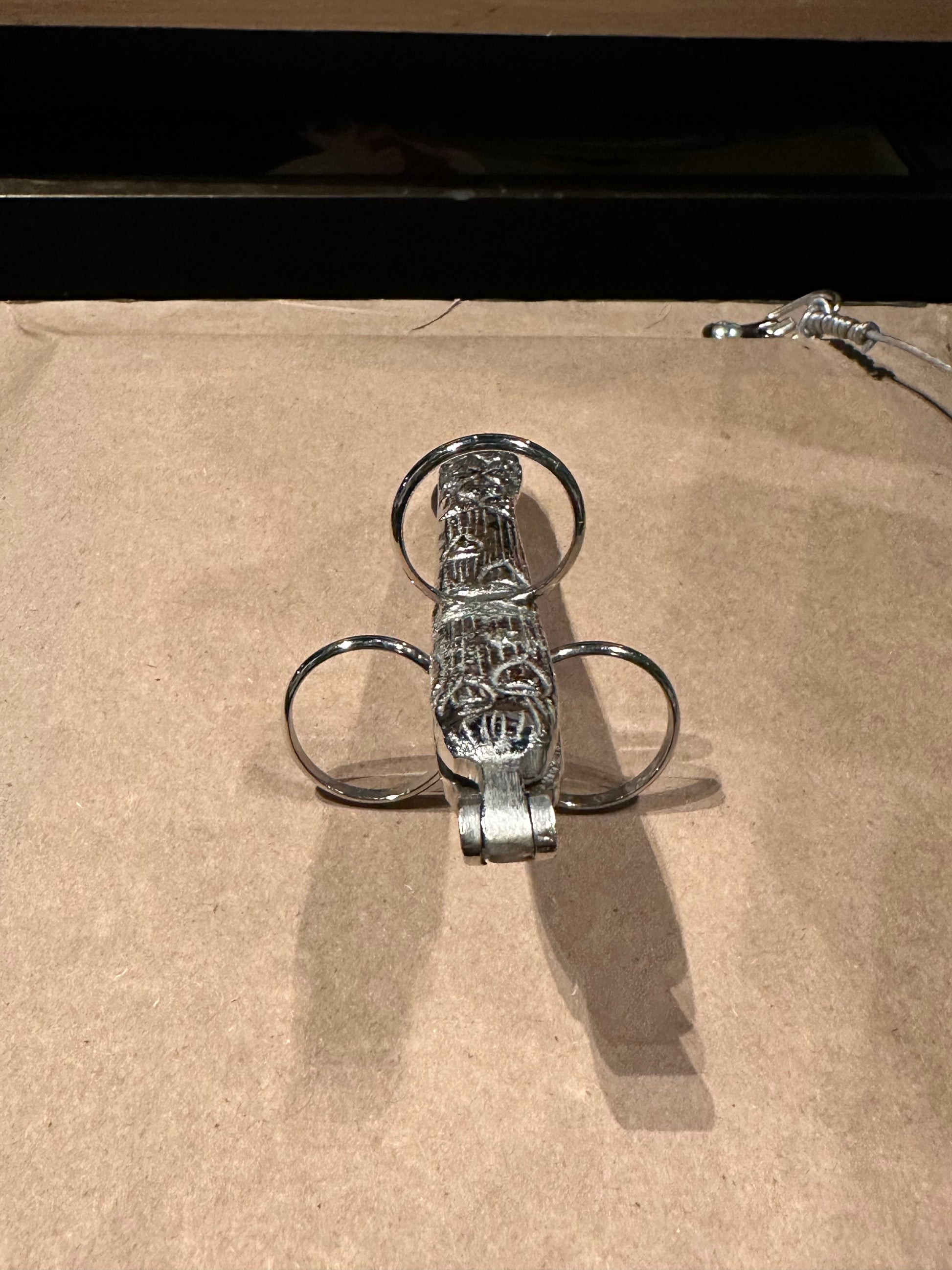 Hinged silver plate asparagus utensil standing on end, ornate handle and finger loops