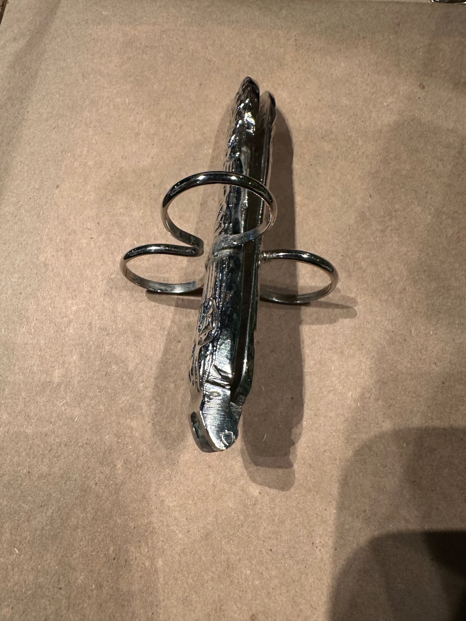 Side view of a hinged asparagus utensil showing its folded form and three finger loops