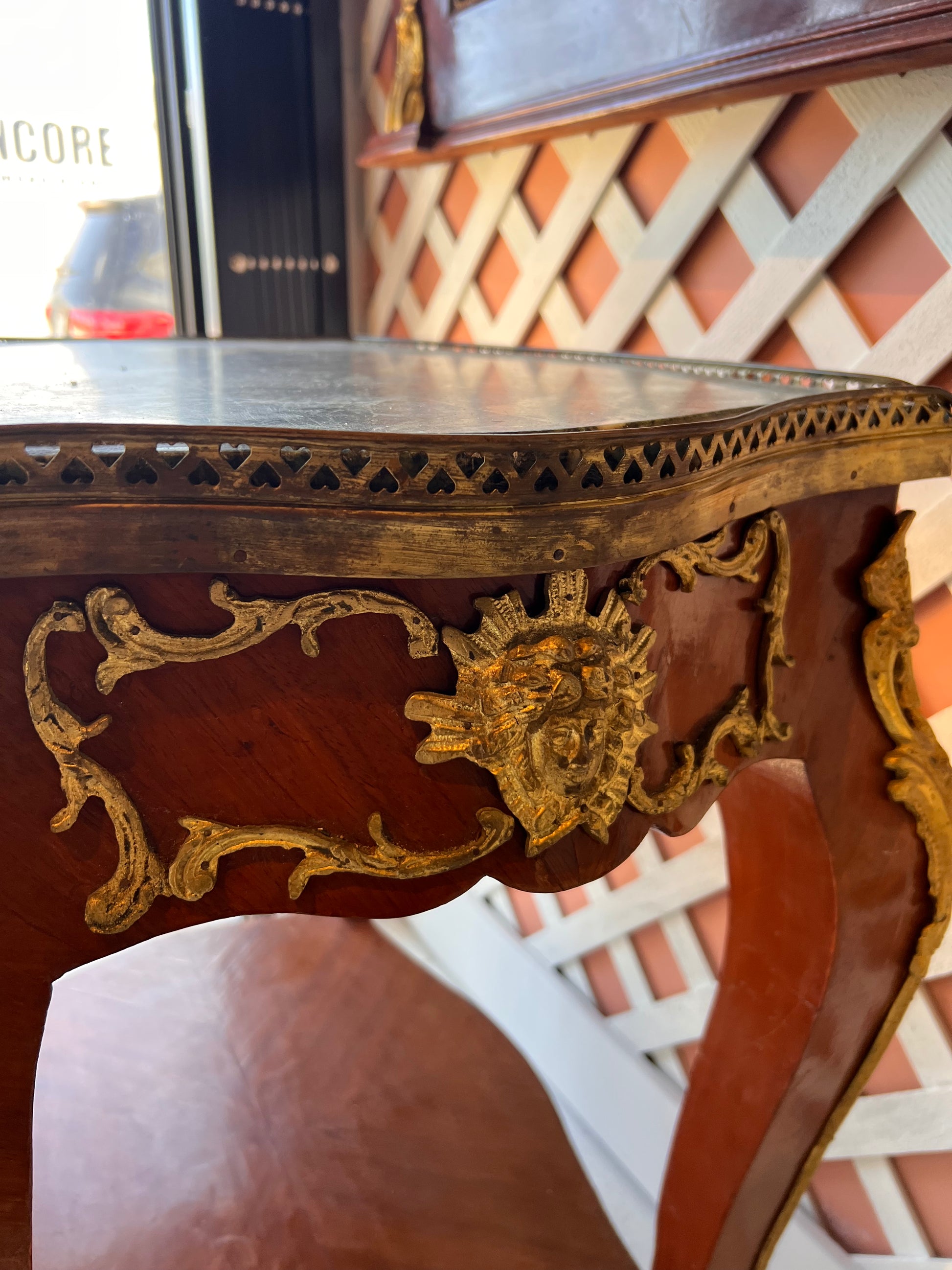 Close-up of the side table's apron with gilt ormolu mask mount and green marble gallery edge