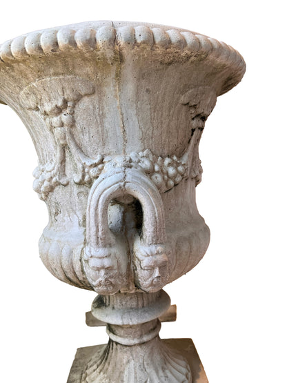 Close-up of a concrete urn bowl showing a figural mask handle and carved fruit swags