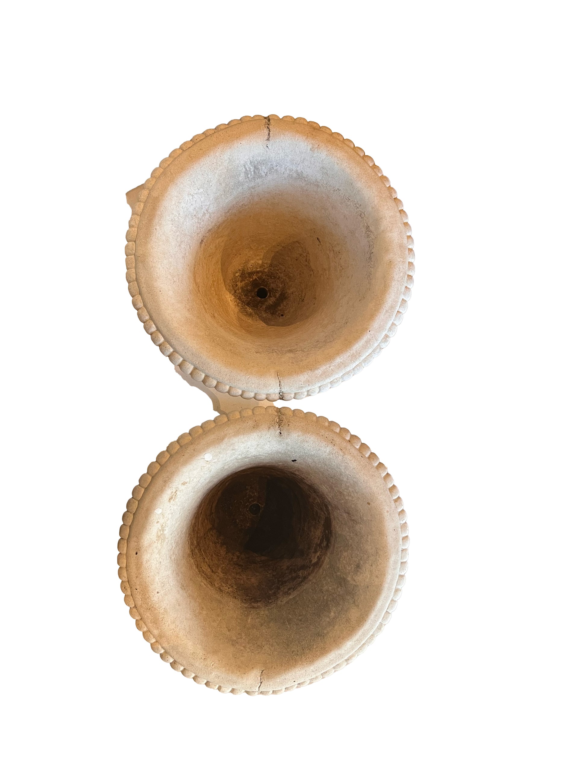 Top-down view into both concrete urns showing beaded rims and aged interior bowls