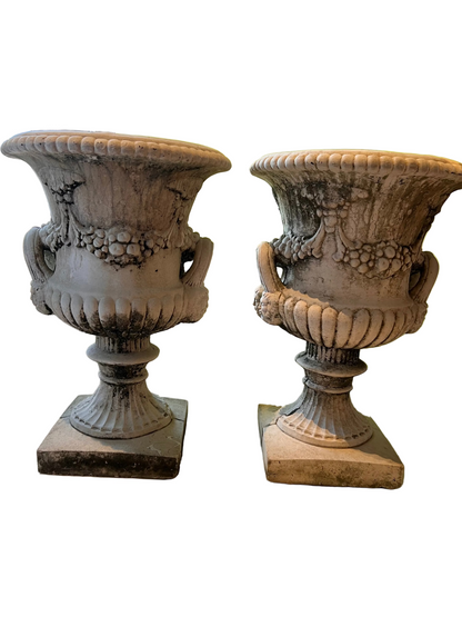 Pair of concrete Regency urns, three-quarter view, fluted pedestals and weathered surface
