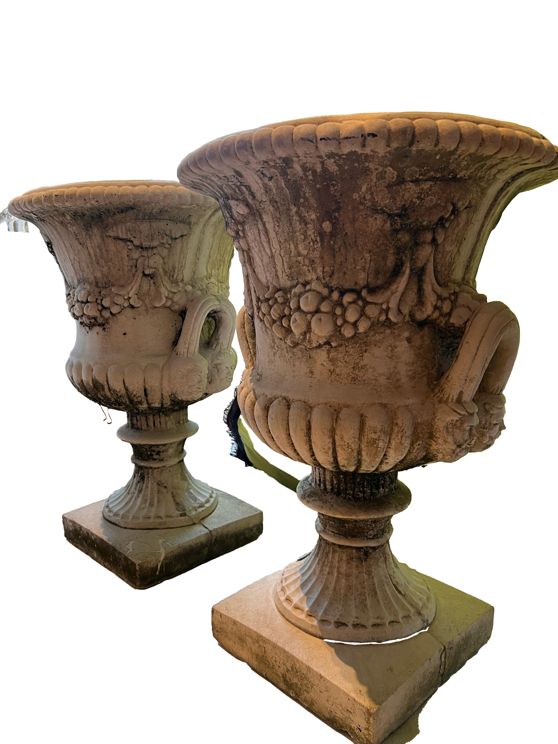 Two concrete Regency urns at an angle, one in foreground, mossy weathered surface and gadrooned bowls