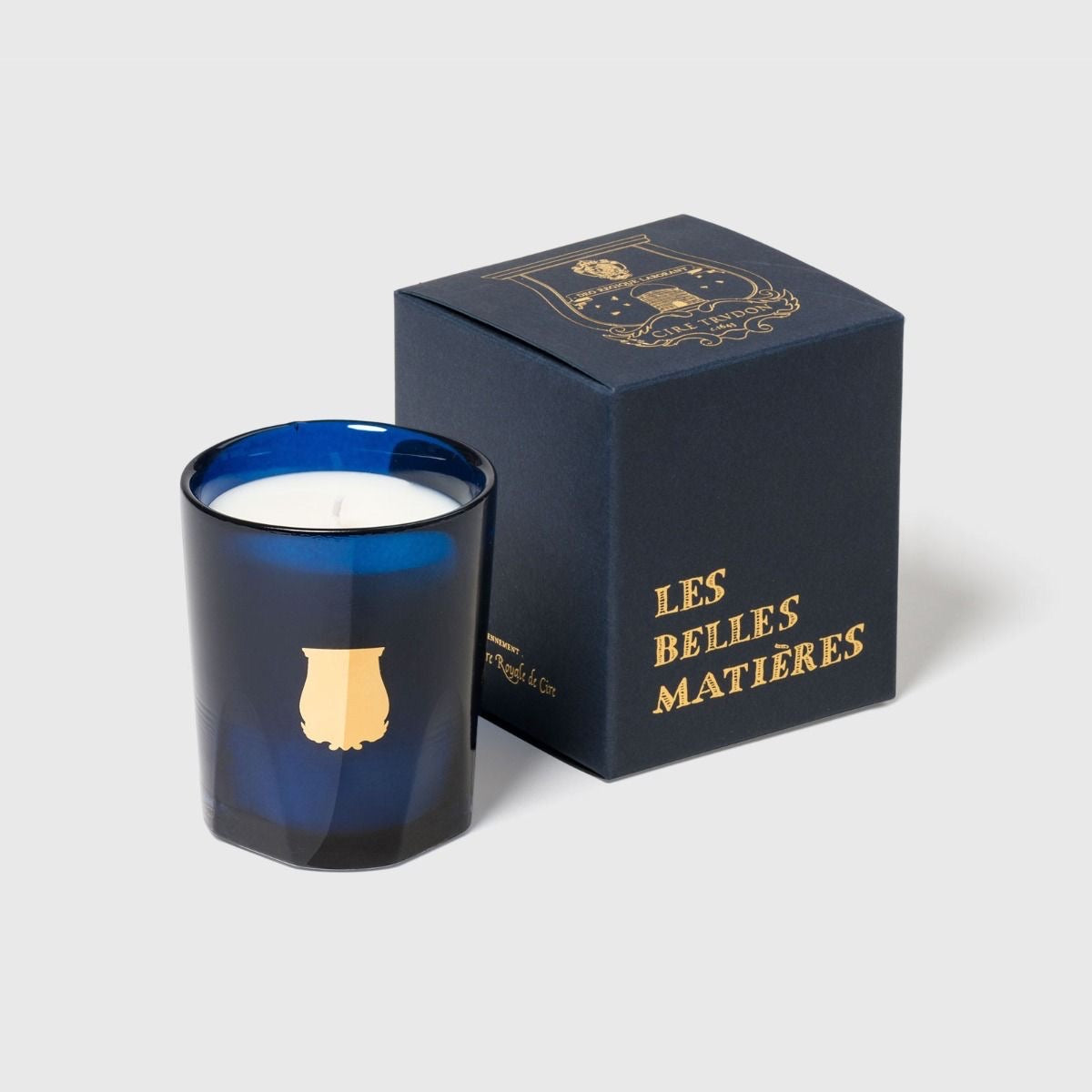 Trudon Madurai petite candle beside navy 'Les Belles Matieres' gift box, blue glass