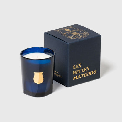 Trudon Madurai petite candle beside navy 'Les Belles Matieres' gift box, blue glass