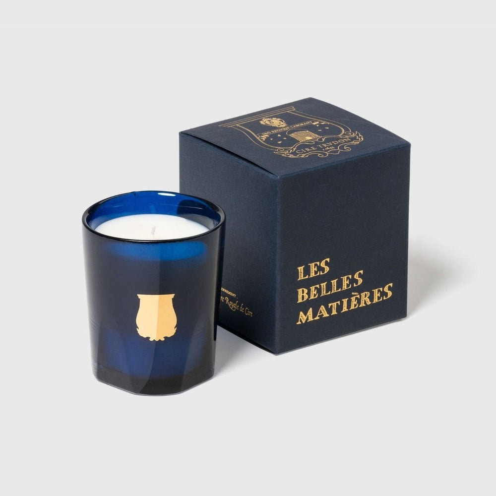 Trudon Salta petite candle beside navy 'Les Belles Matieres' gift box, blue glass