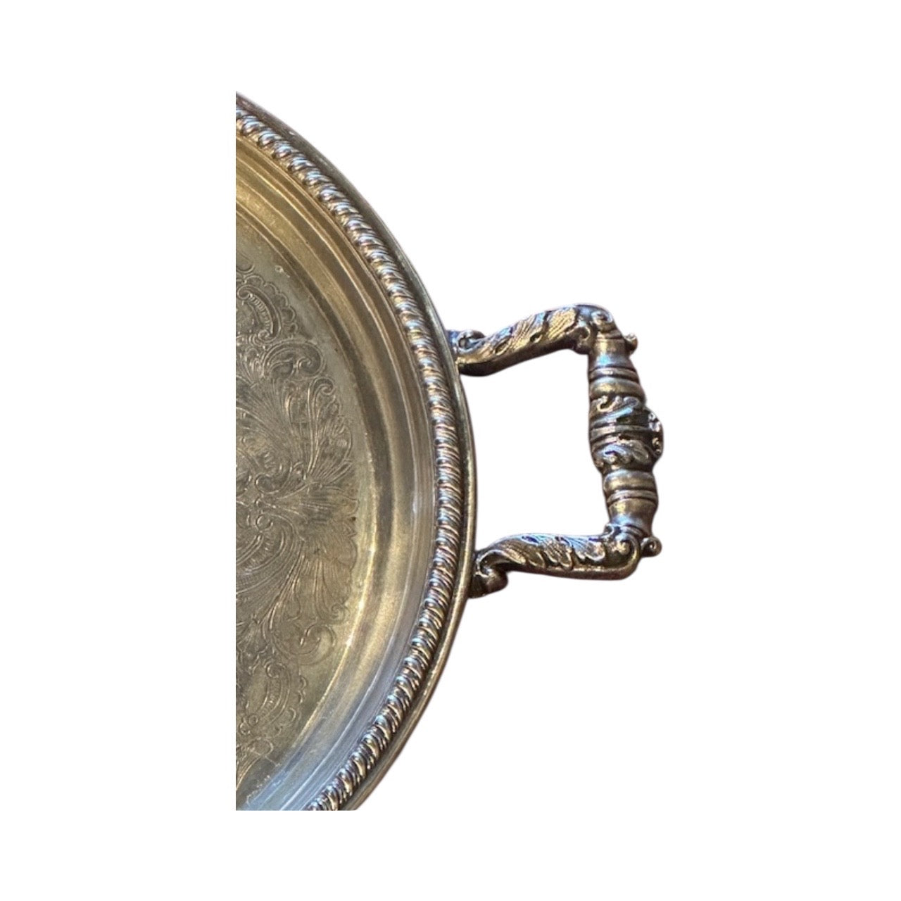 Close-up of round silver-plate tray's ornate scrolled handle and gadroon rope rim