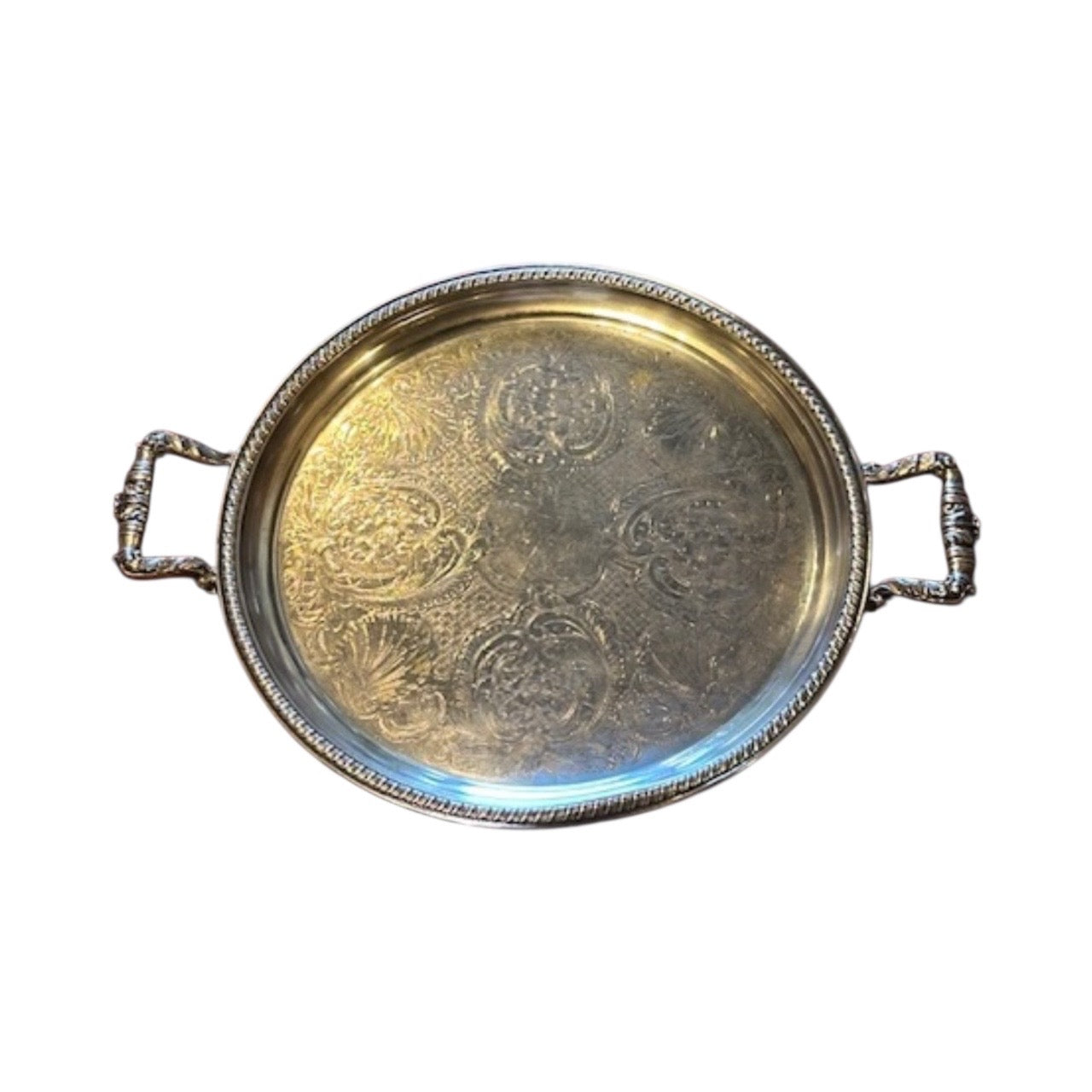 Angled view of vintage round silver-plate tray with engraved center and two ornate handles
