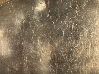 Macro close-up of the oval tray's silver-plate surface covered in fine scratches.
