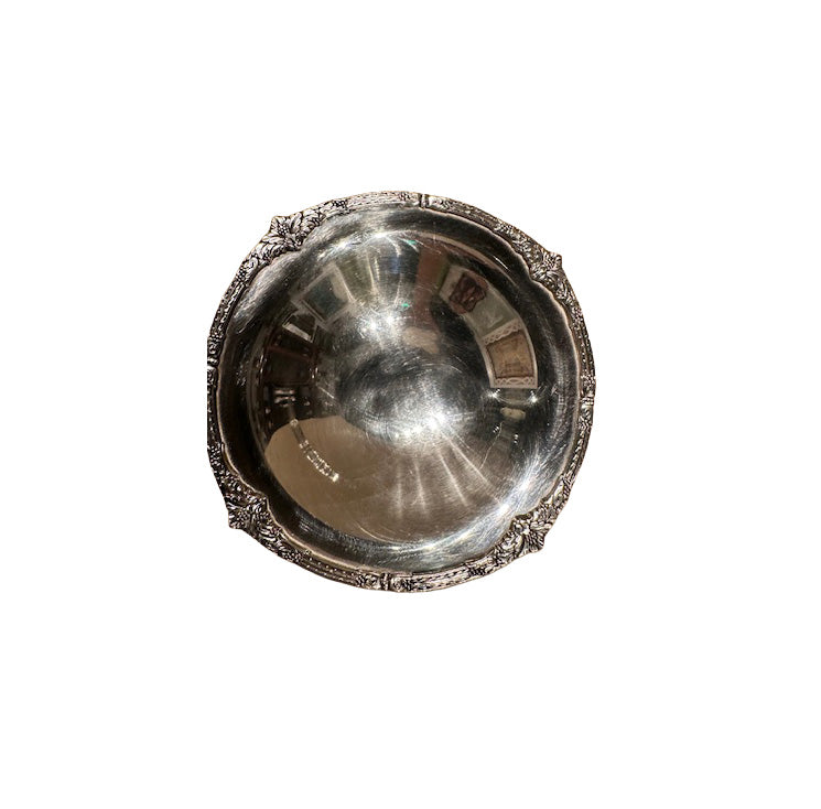 Top-down view into the compote's polished bowl with an ornate floral-scrolled rim.