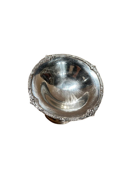 Angled view into the compote's polished bowl, showing the ornate scrolled border at the rim.