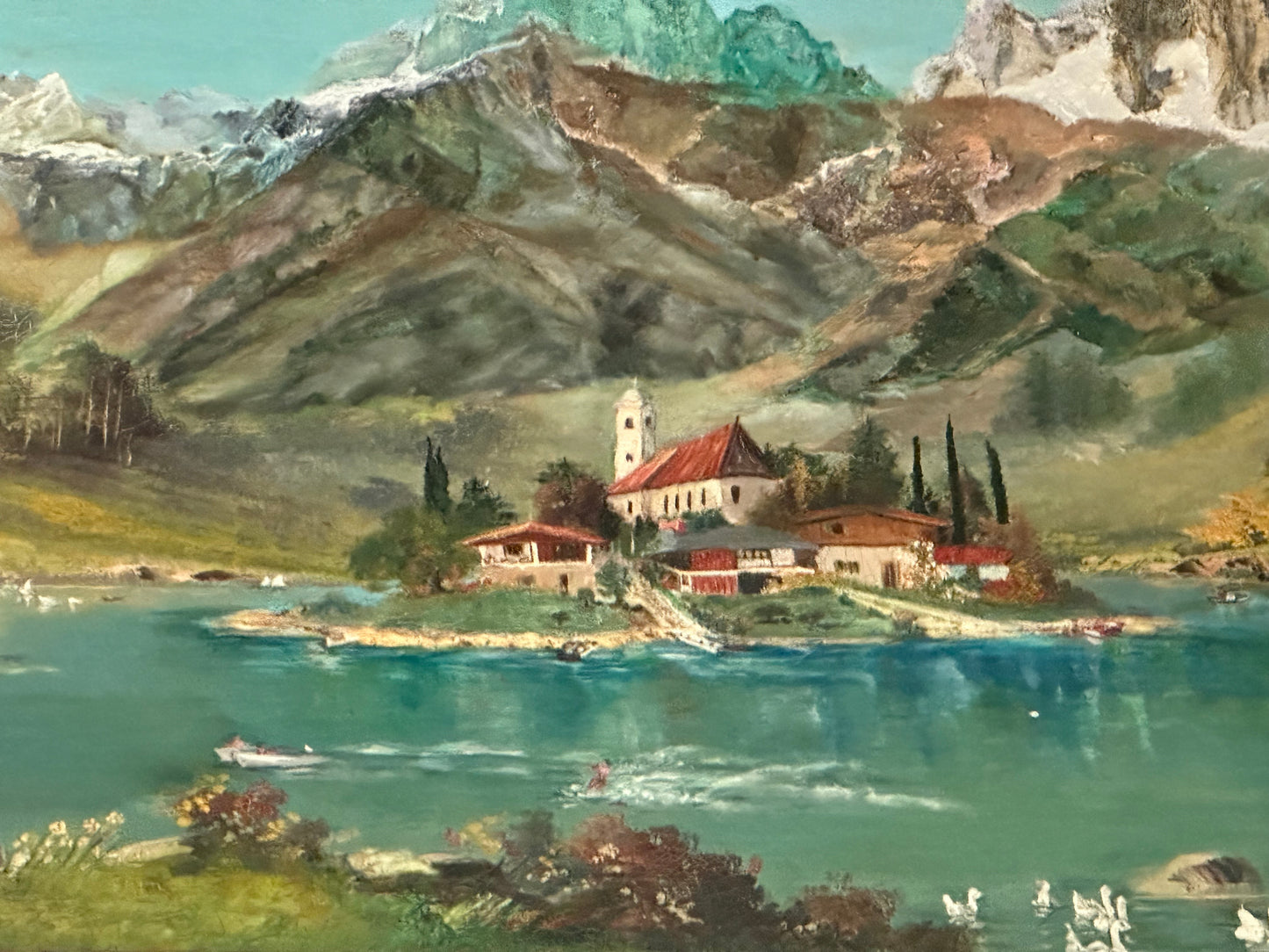 Detail of the alpine painting's island village: church steeple, red-roofed chalets and cypress trees by a turquoise lake.