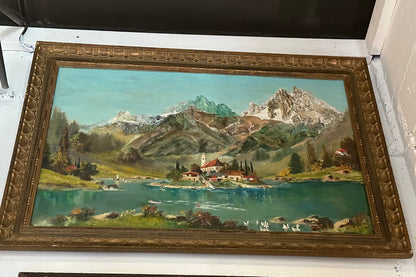 Large-scale framed oil of an alpine lake, island village and snowy peaks, in an ornate carved gilt frame.