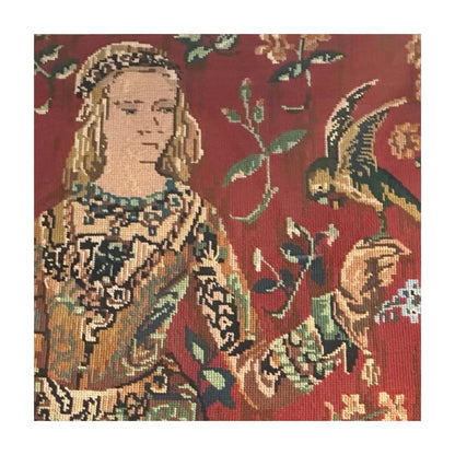 Detail of restored needlepoint: a medieval lady in patterned gown beside a parrot on red ground