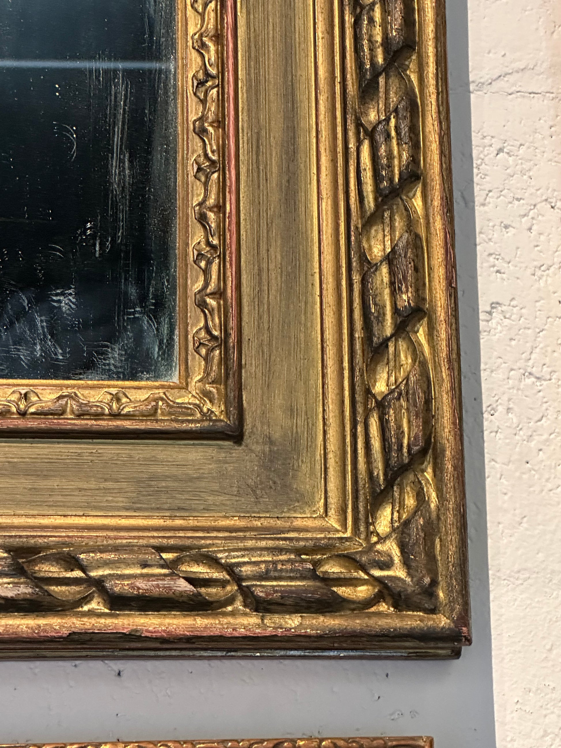 Close-up of the gilt mirror frame's braided and carved gold molding at one corner