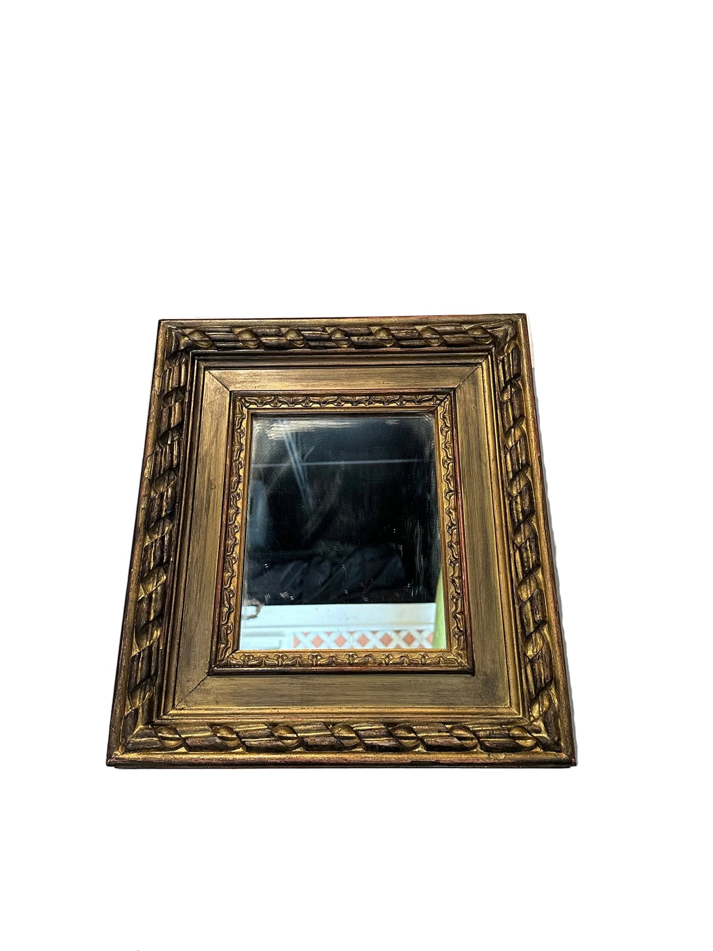 Small carved gilt-framed mirror, angled front view with foxed antique mirror plate