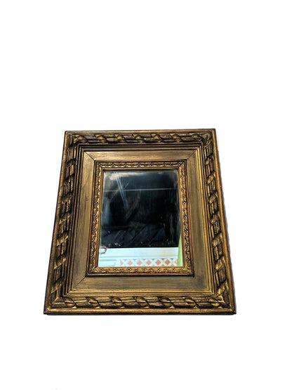 Small carved gilt-framed mirror, angled front view with foxed antique mirror plate