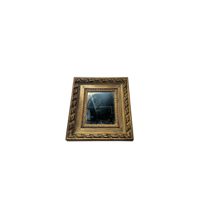Small carved gilt-framed mirror, angled view showing the distressed antiqued glass