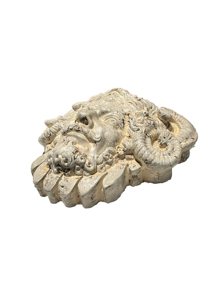 Cast concrete mascaron, angled side view of the bearded face and curled ram's horns.
