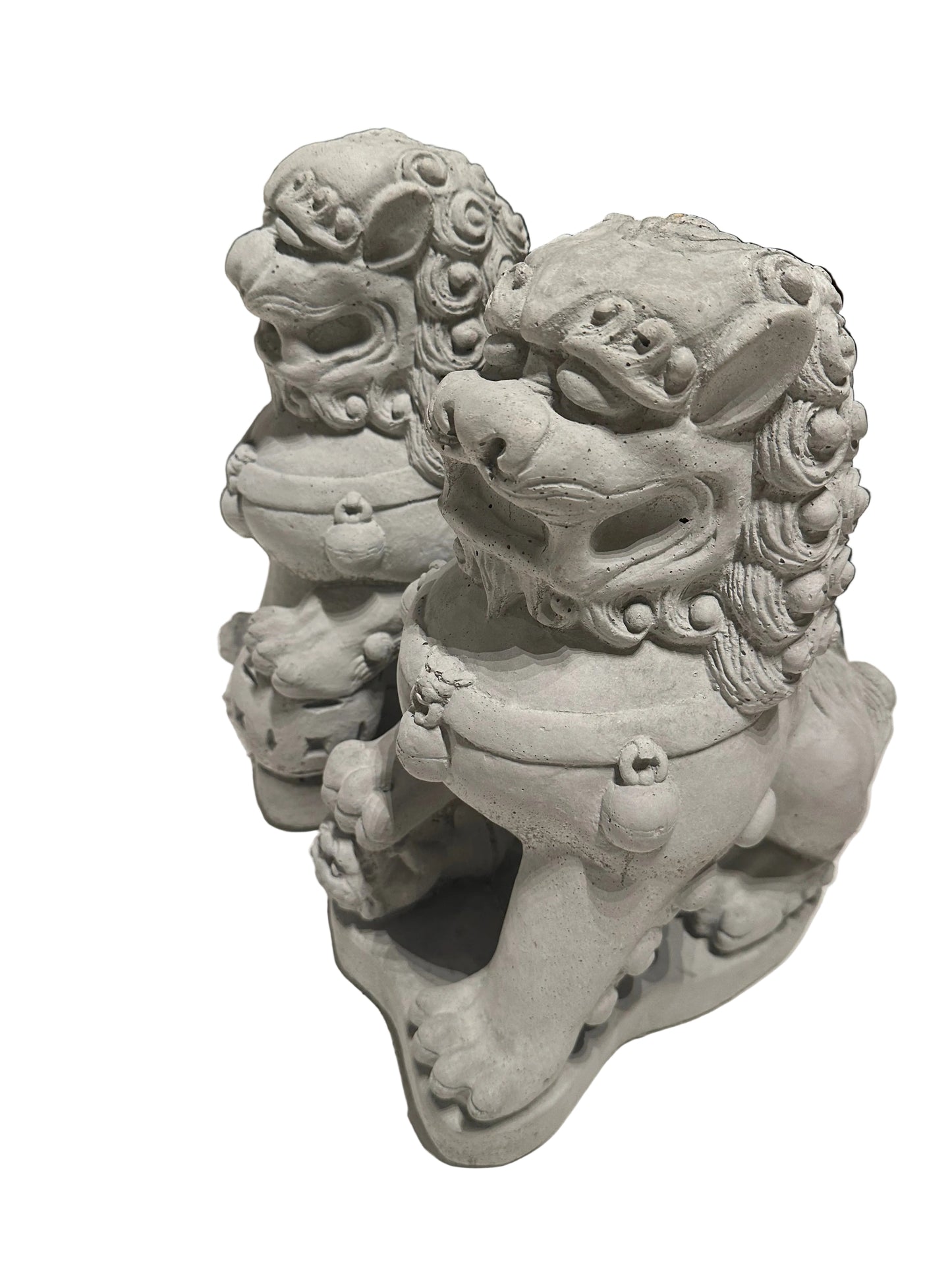 Close three-quarter view of cast concrete Foo dogs' carved maned faces