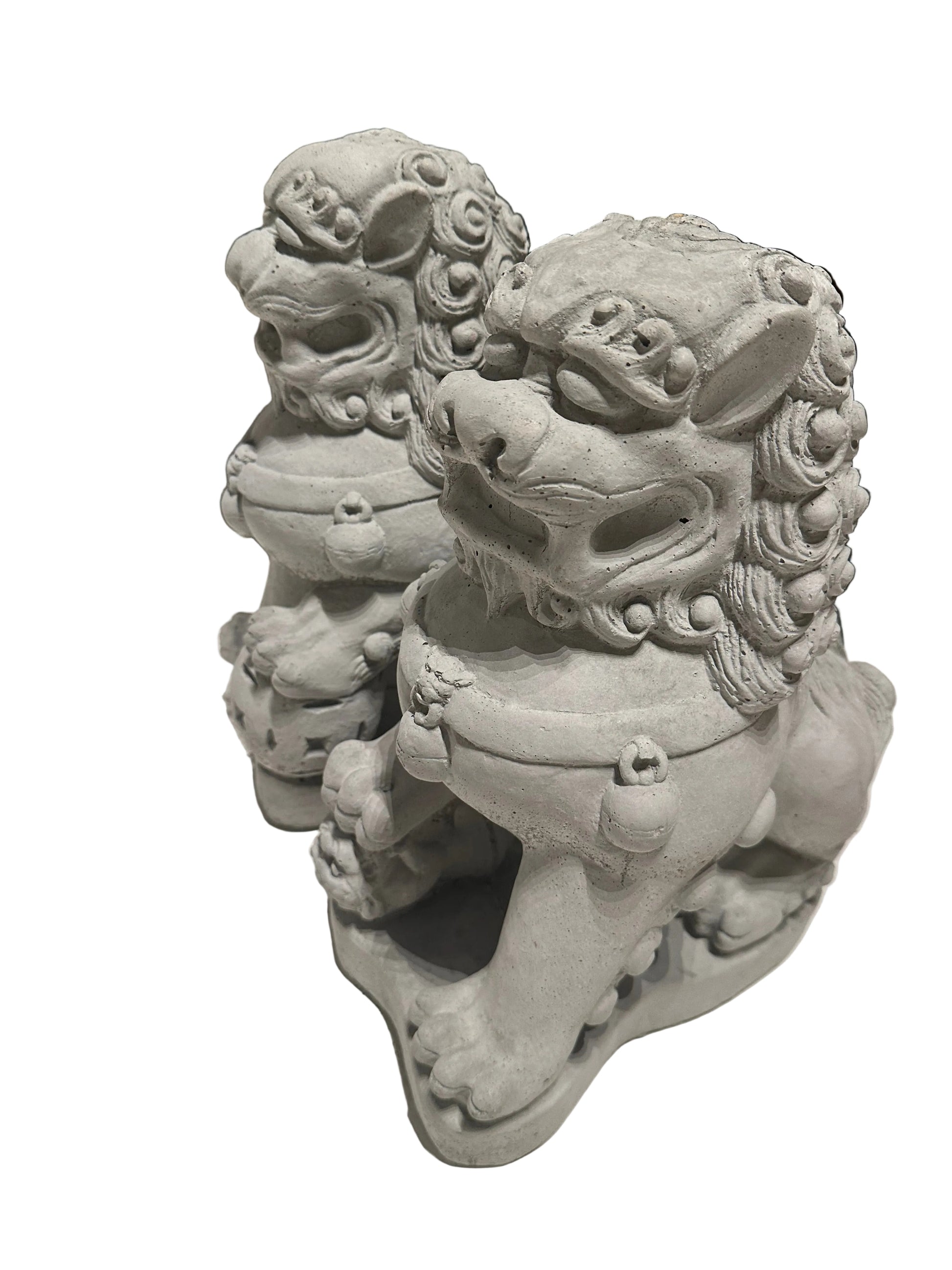 Close three-quarter view of cast concrete Foo dogs' carved maned faces