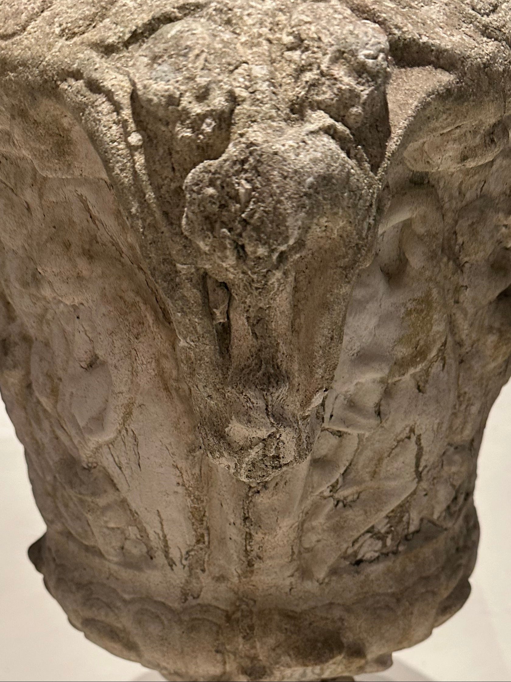 Detail of concrete urn relief showing weathered foliate and figural carving