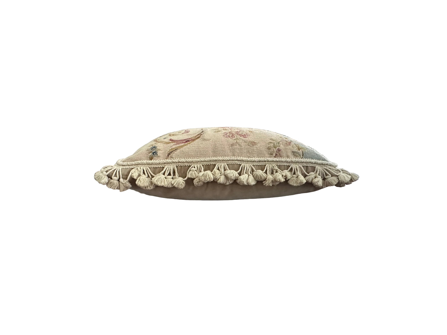 Side profile of floral needlepoint pillow top edge with tassel fringe