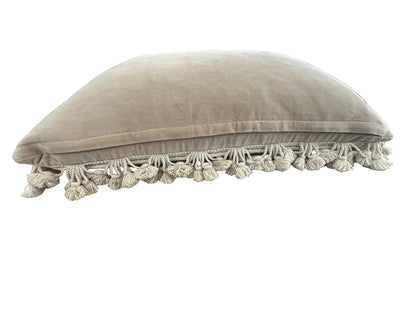 Side profile of needlepoint pillow, beige velvet back and cotton tassel fringe