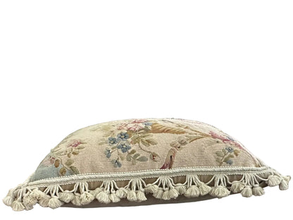 Side angle of needlepoint pillow showing floral motif and full cotton tassel fringe