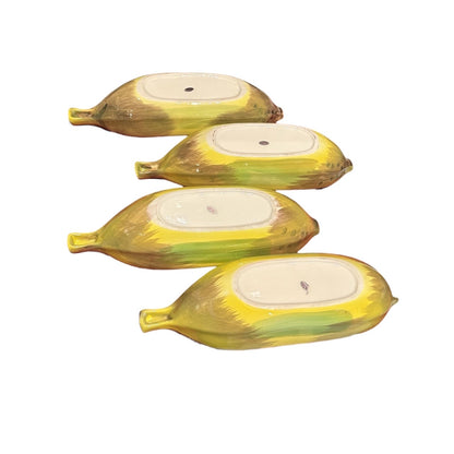 Four banana split bowls shown from underside, yellow and green hand-painted banana exteriors with white oval bases.