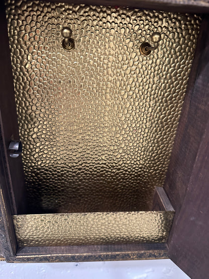 Interior of brass cabinet with dimpled gilt lining and two mounting hooks.