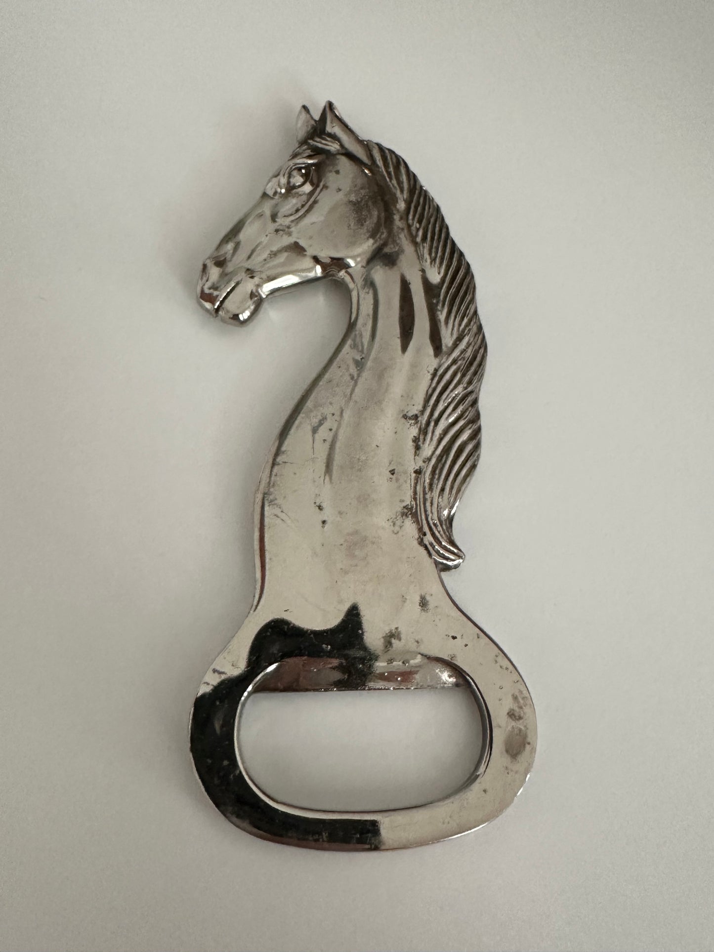Vintage silver plate horse-head bottle opener showing facial detail and opener notch.