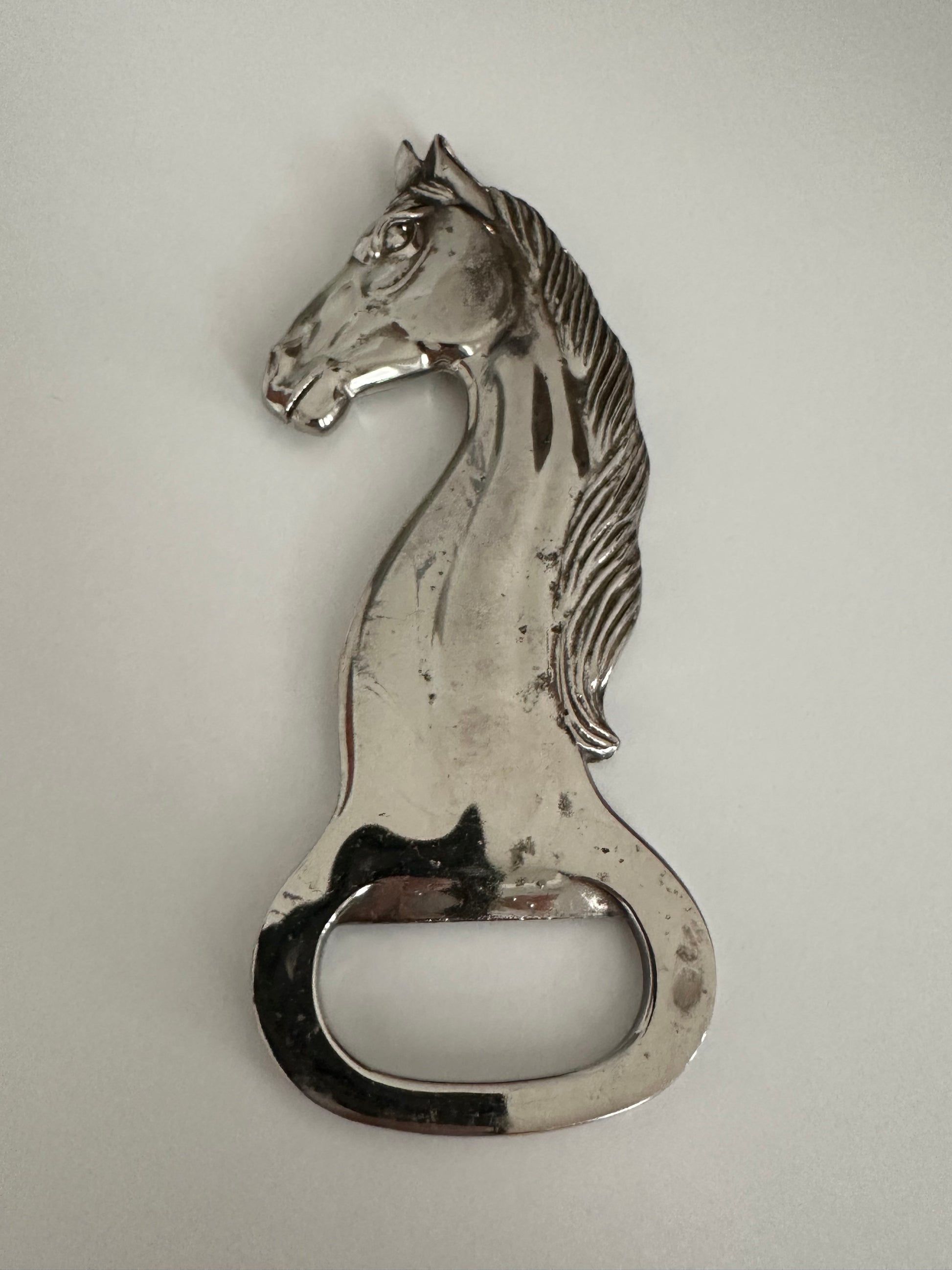 Vintage silver plate horse-head bottle opener showing facial detail and opener notch.