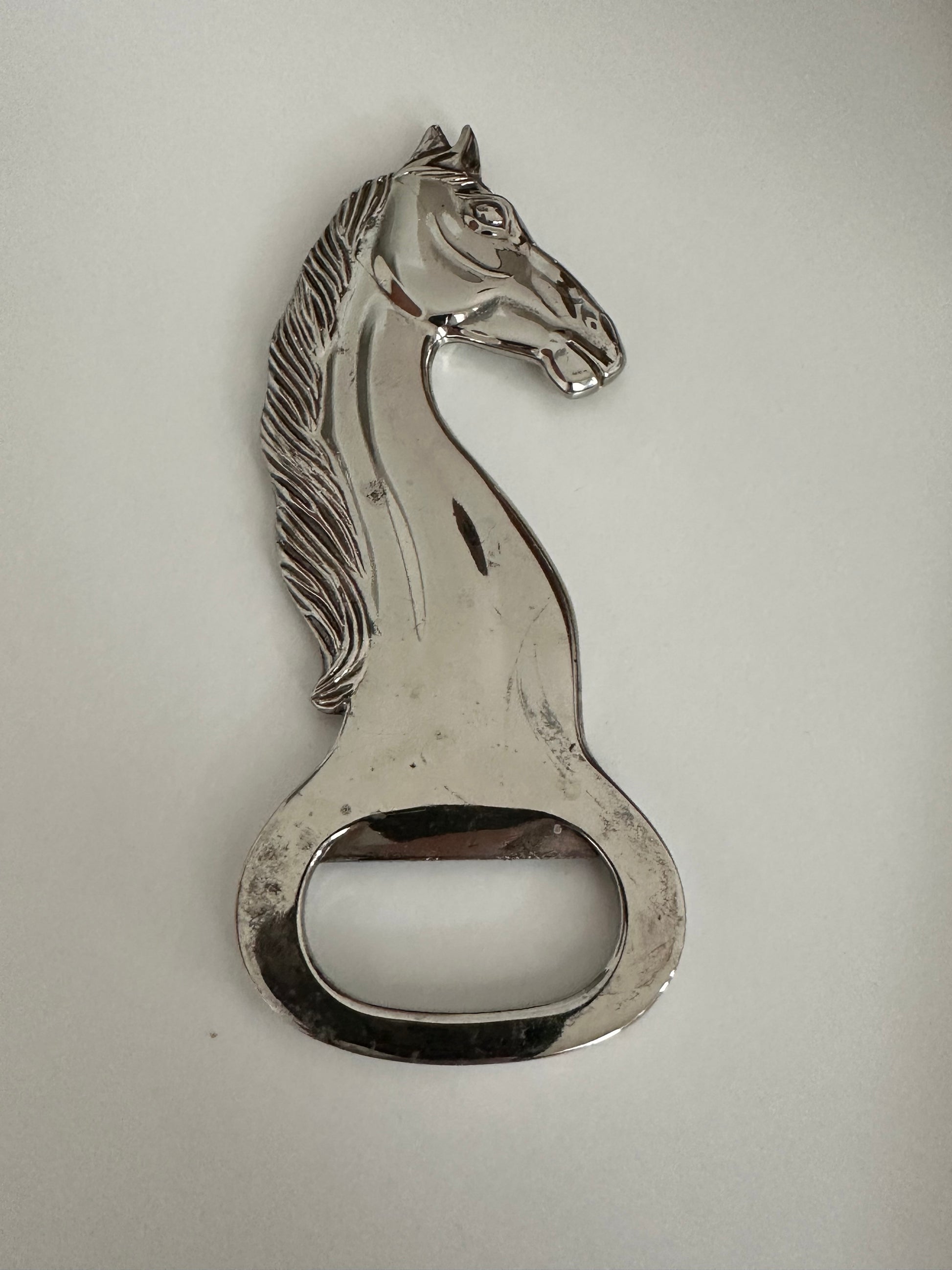 Vintage silver plate horse-head bottle opener, detailed view of mane and bottle-cap lifter.