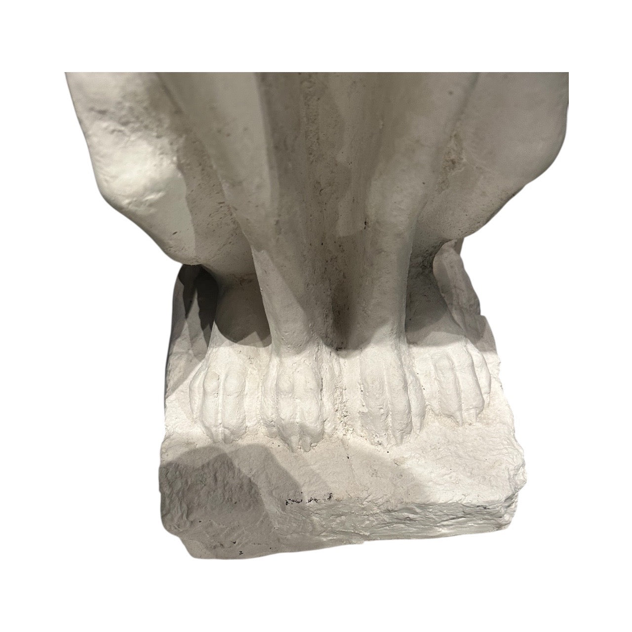 Close-up of white greyhound statue's front paws on a rough-cast plaster base