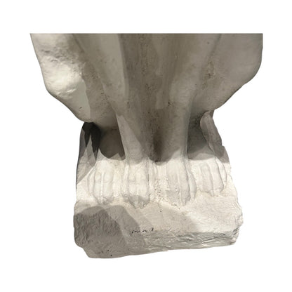 Close-up of white greyhound statue's front paws on a rough-cast plaster base