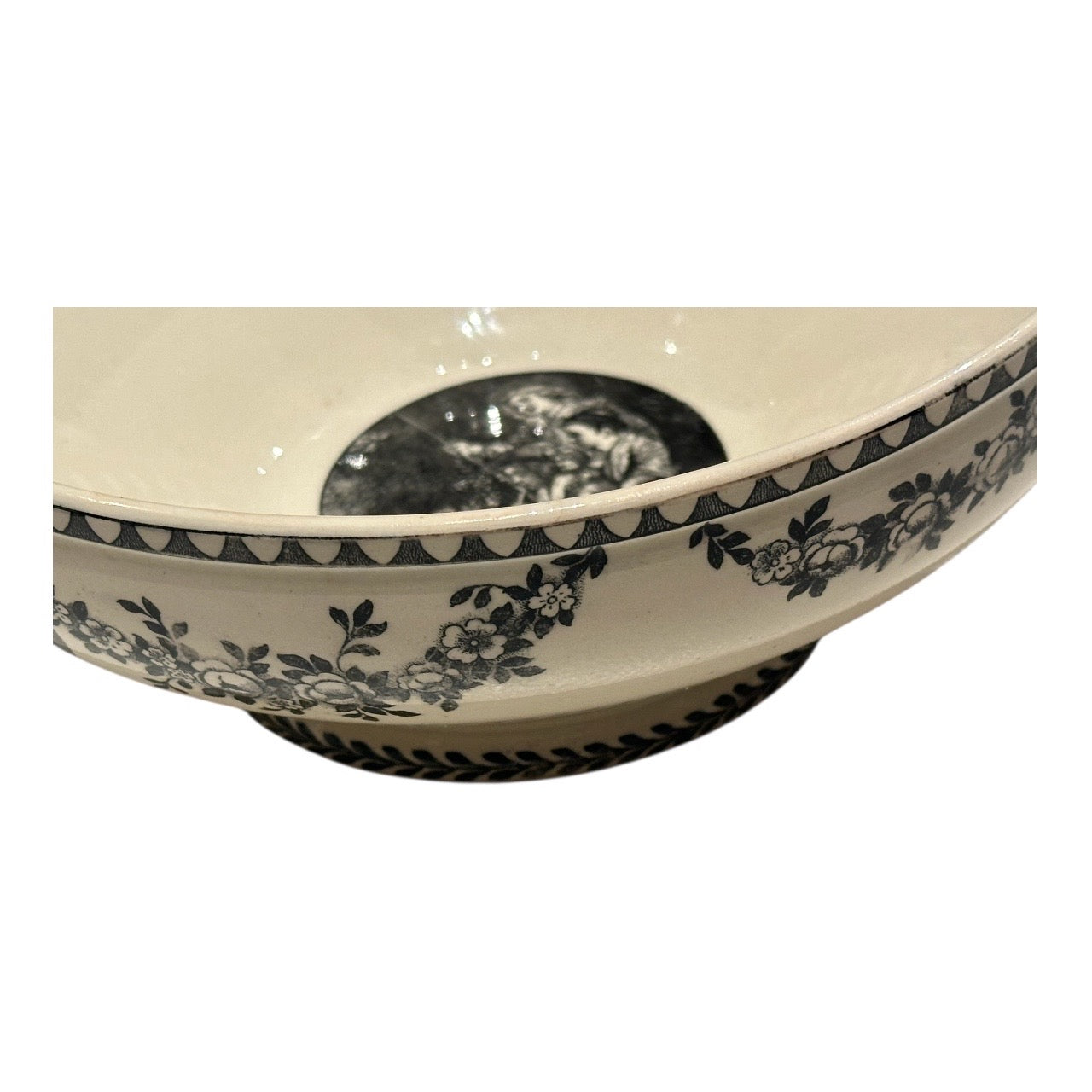 Side view of the transferware bowl showing floral black décor and footed base
