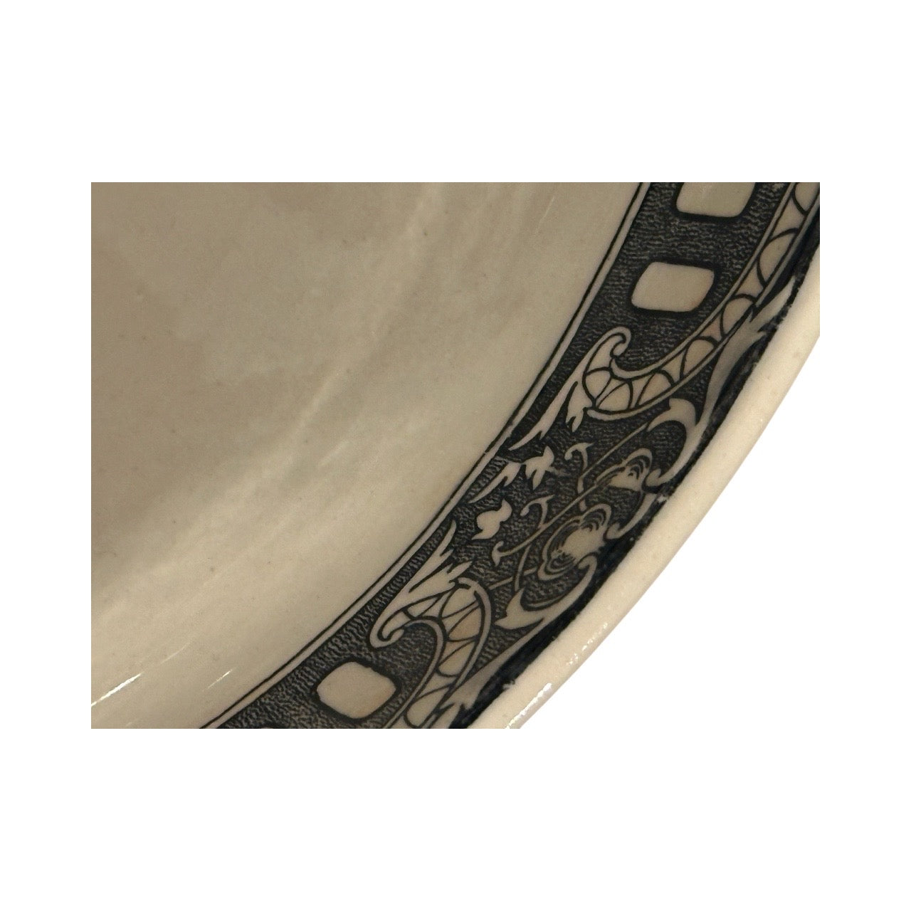 Close-up of the black scrollwork border band on the cream transferware bowl