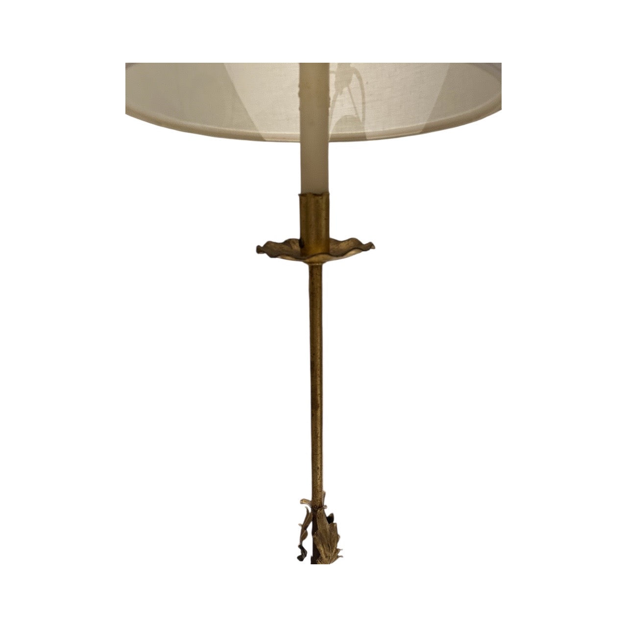 Lower portion of the gilt floor lamp showing slim stem and leaf-form finial beneath the shade