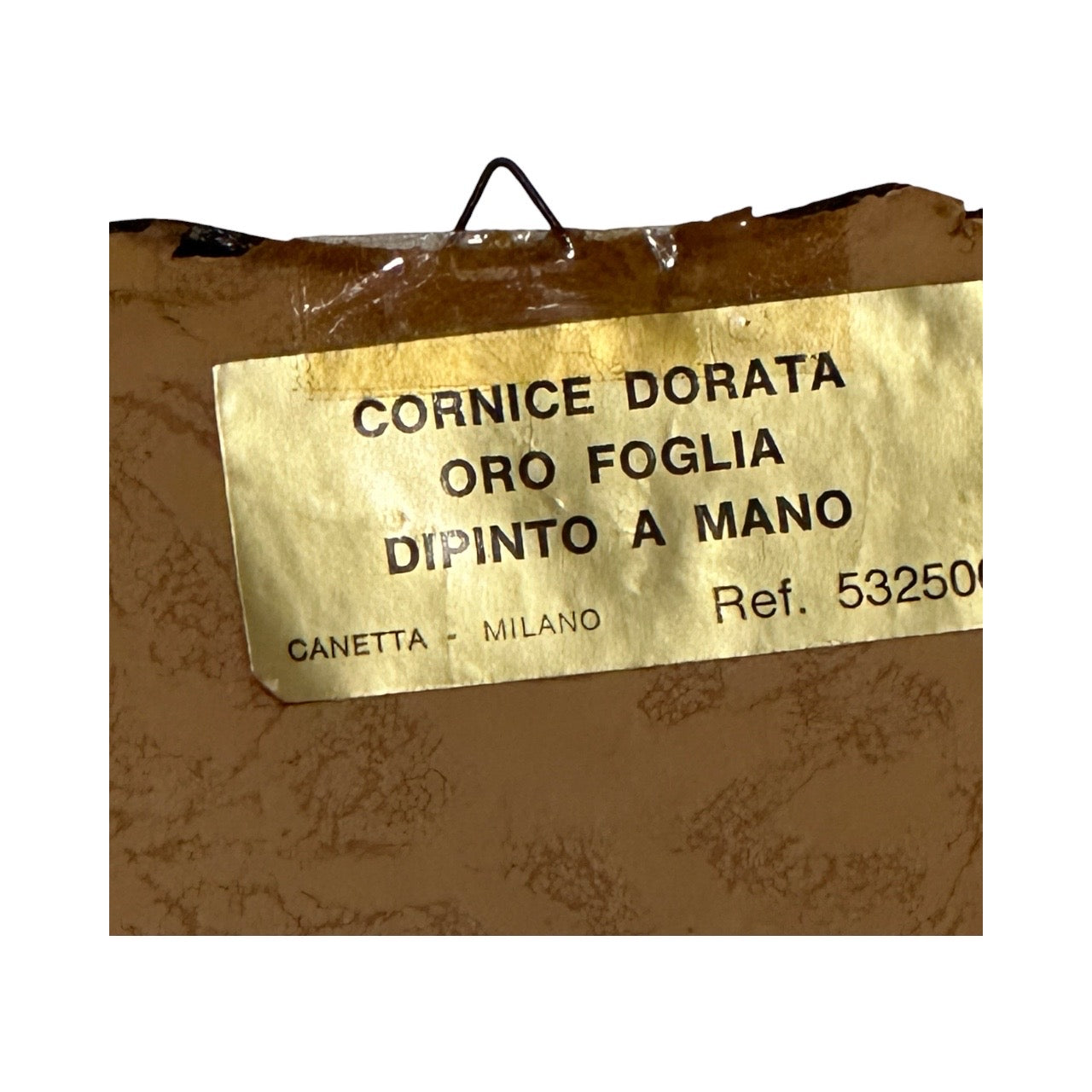 Close-up of Italian frame's back label reading Cornice Dorata Oro Foglia Dipinto a Mano, Canetta Milano