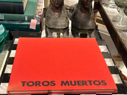 Vintage book Toros Muertos, red cloth cover displayed on tray beside bronze sphinx figures