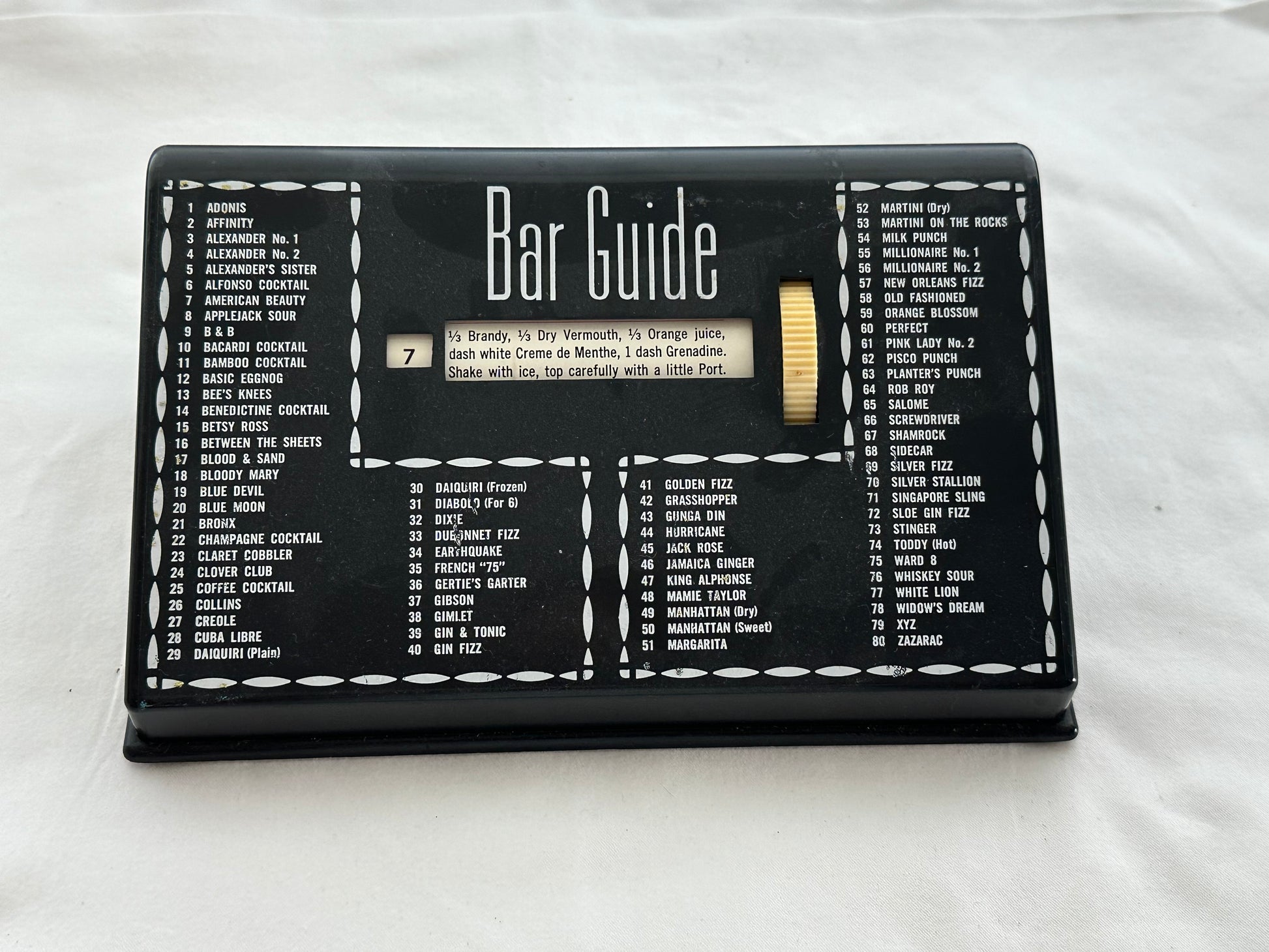 MCM black plastic Bar Guide front view listing 80 numbered cocktails with central recipe window