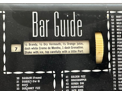 Close-up of MCM Bar Guide face, ivory scroll dial and recipe window listing a brandy cocktail