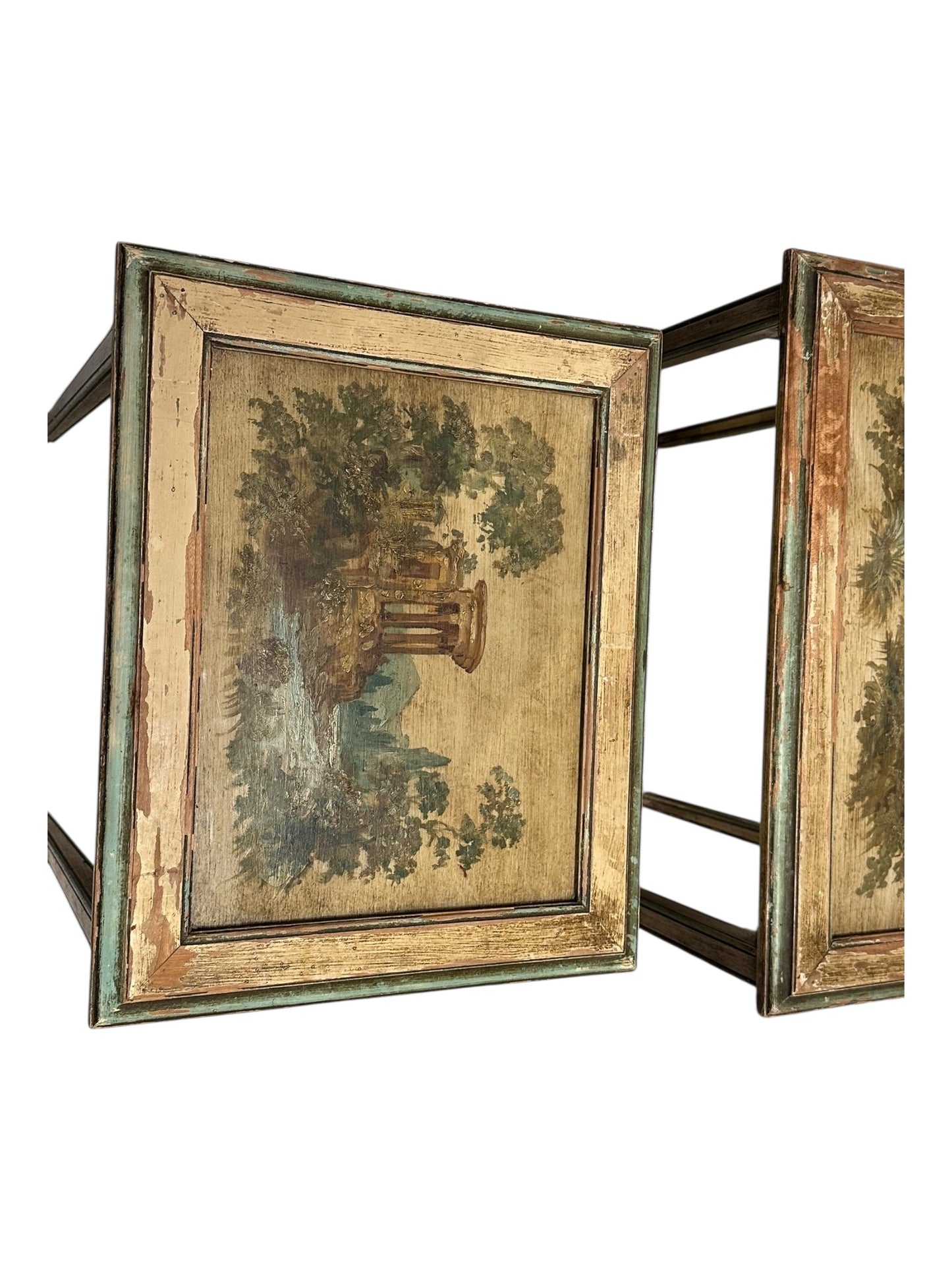 Detail of a nesting table's painted top depicting trees and ruins, with worn green frame.