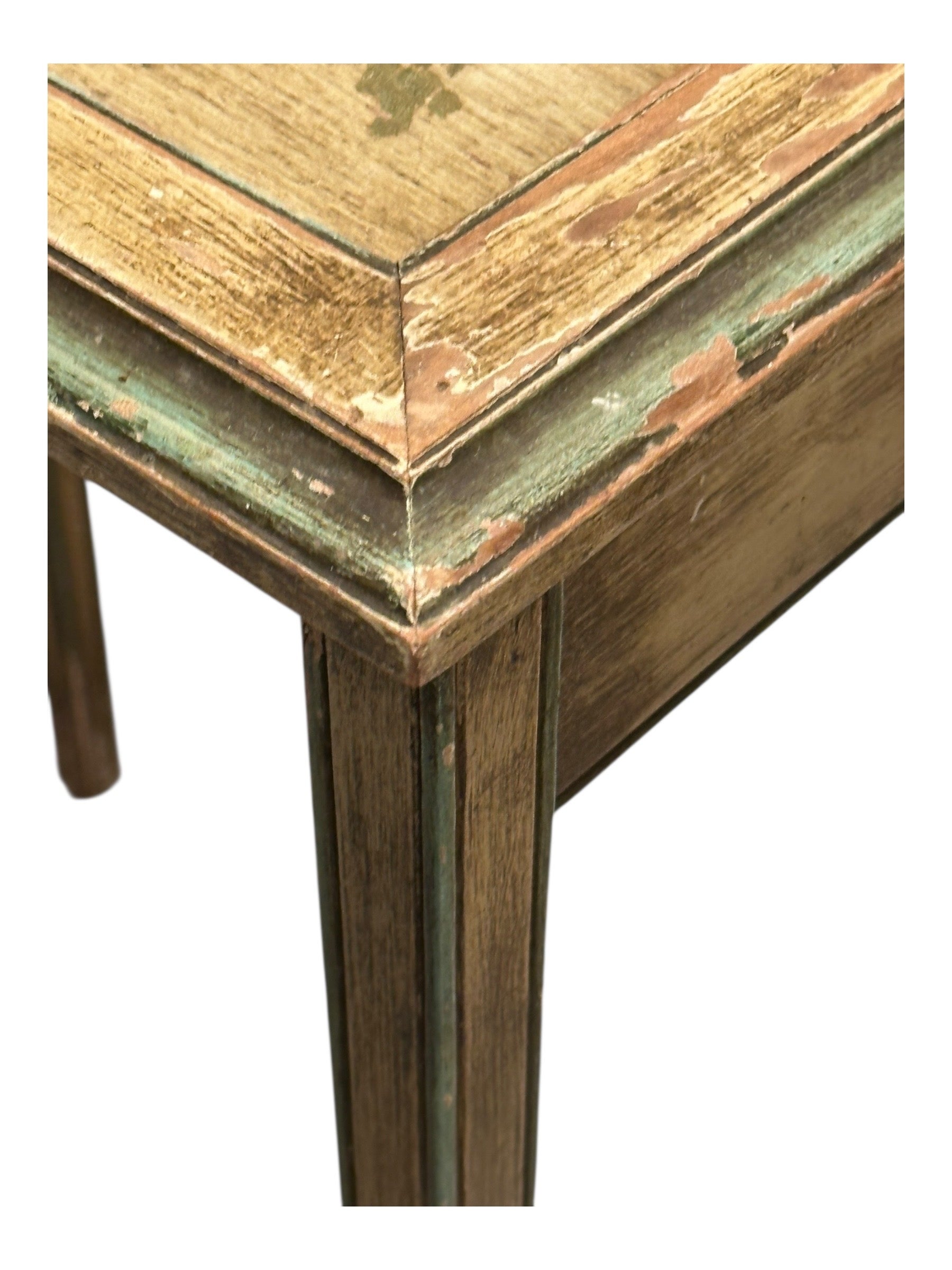 Close-up of a distressed painted table corner and tapered leg.