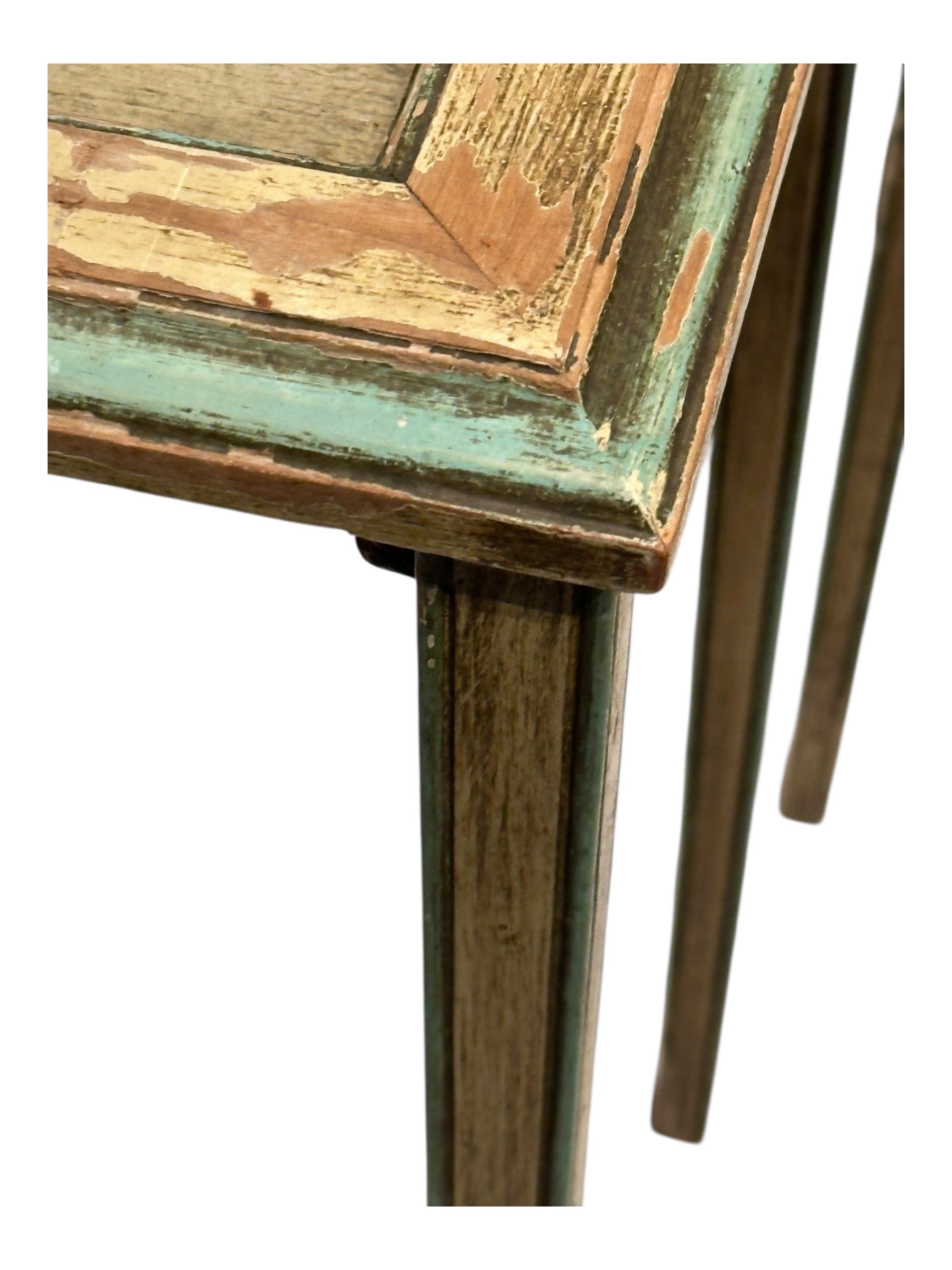 Close-up of a table corner and tapered leg with worn green and gilt distressed paint.