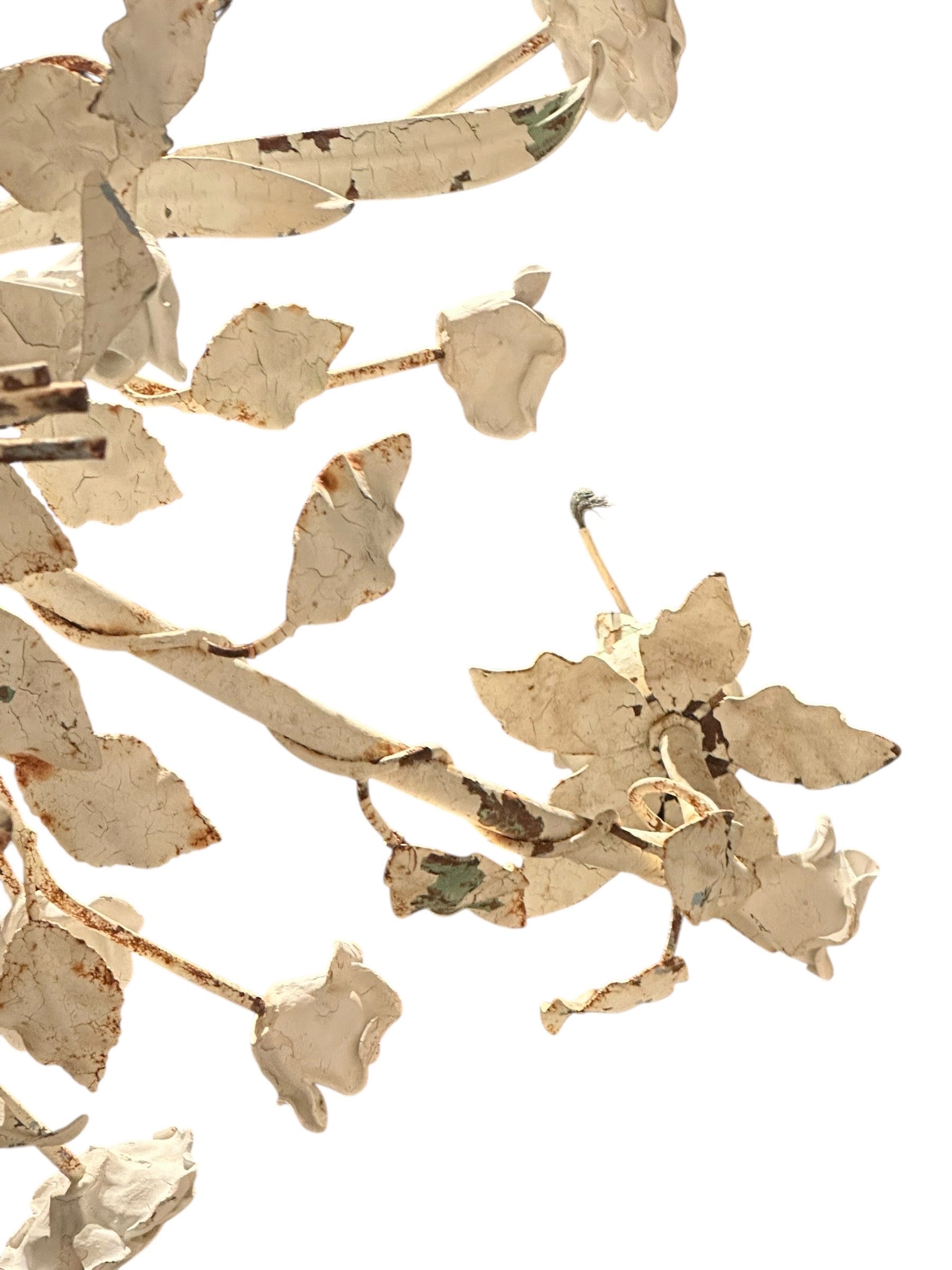 Detail of worn cream floral chandelier branches with metal roses and leaves