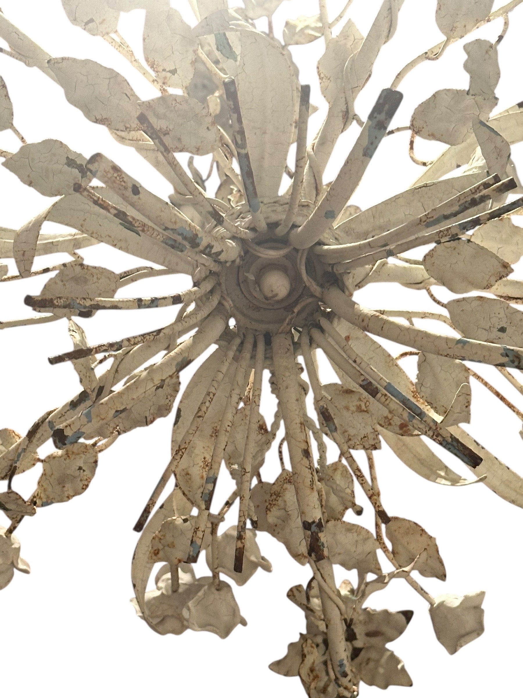 Underside of cream wrought iron floral chandelier showing central rosette and arms