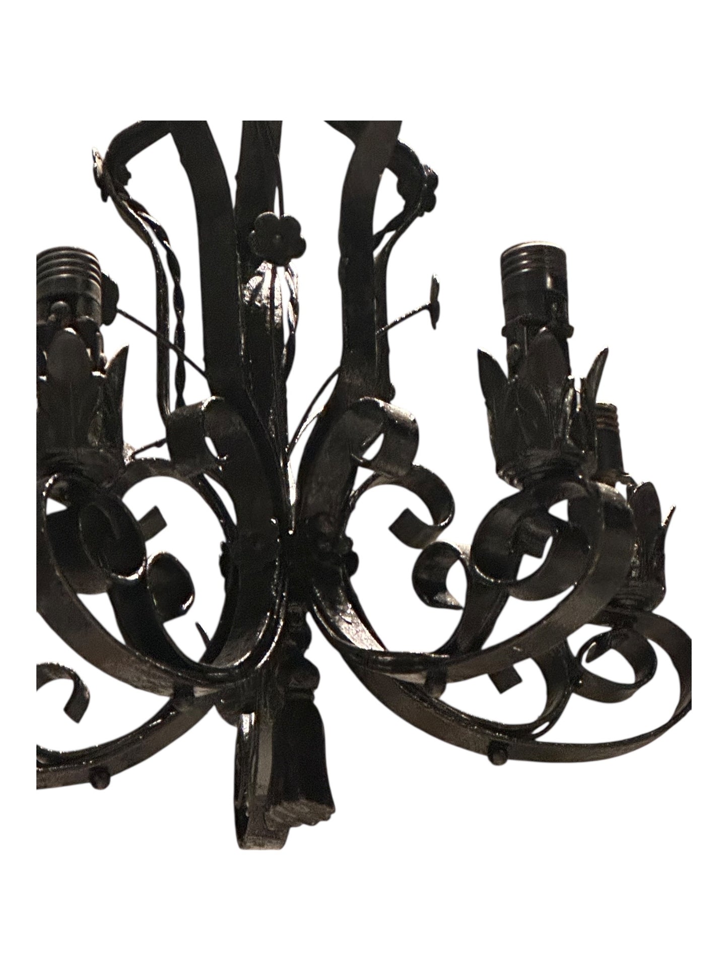 Wrought iron chandelier arm detail with leaf motif and bulb socket, close-up